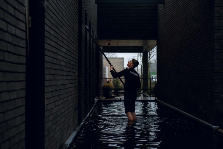 Persoon staat kniehoog in het water en dichterste hoog raam voor bedrijfsreportage.