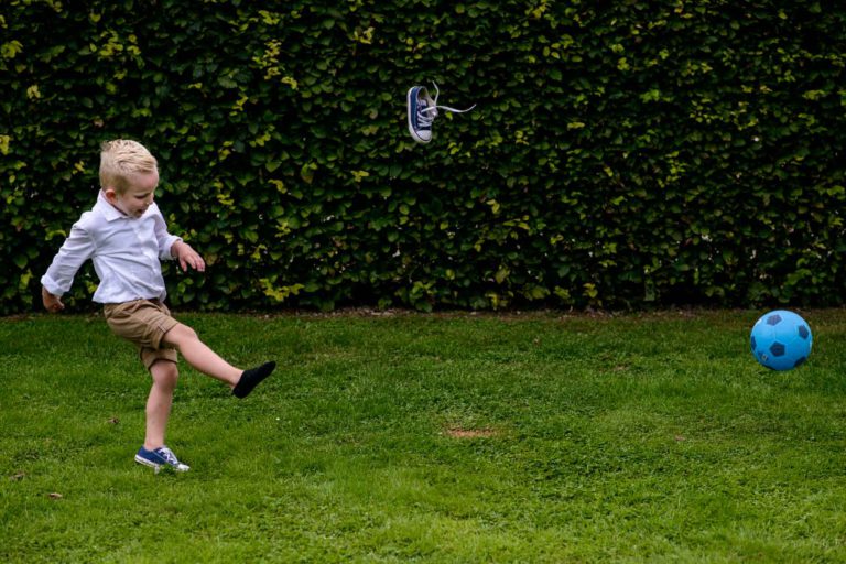 Soort speelt met bal; schoen vloog per ongeluk weg in grasveld.