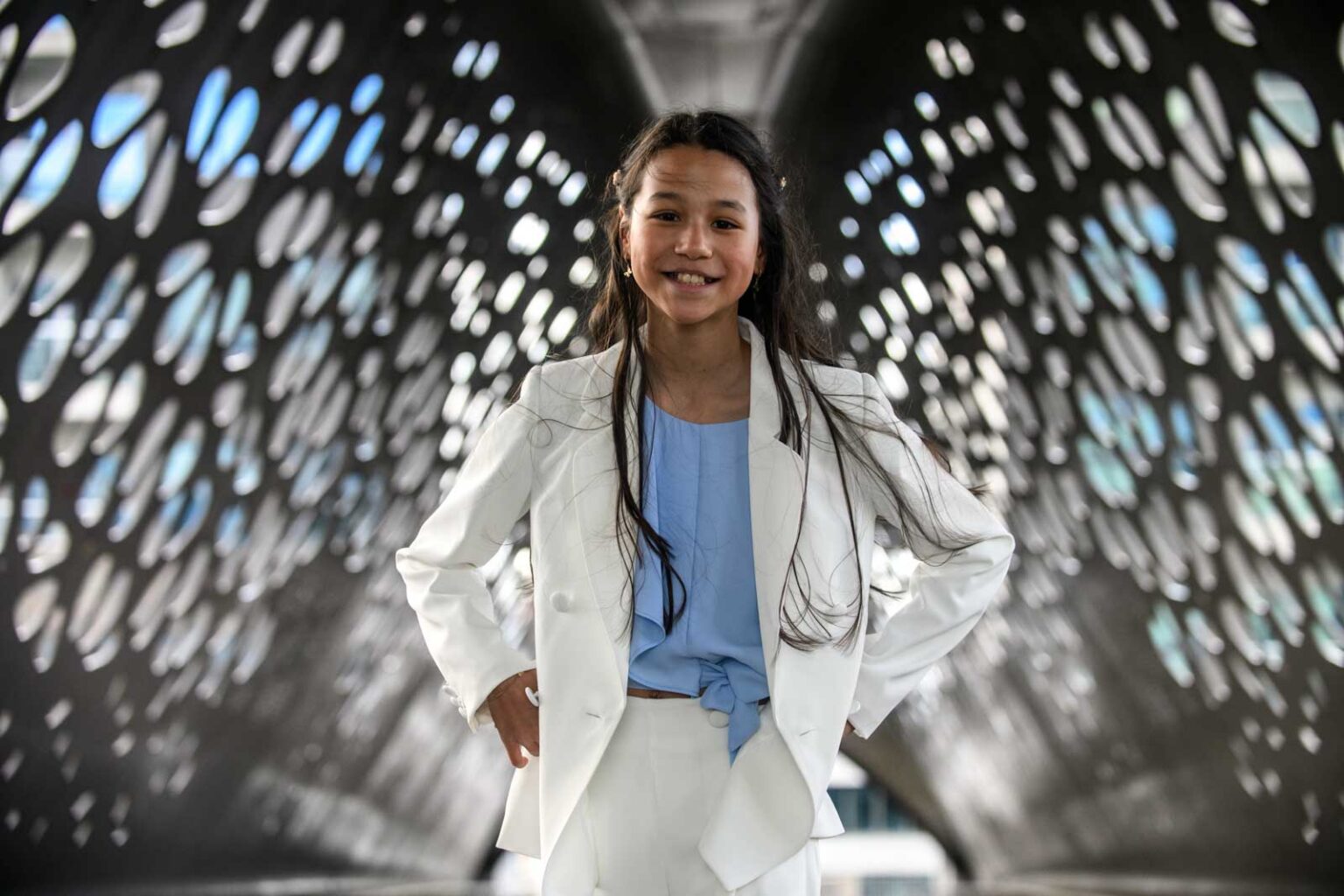 Zelfverzekerd meisje in wit pak poseert in tunnel met ronde uitgesneden wanden.