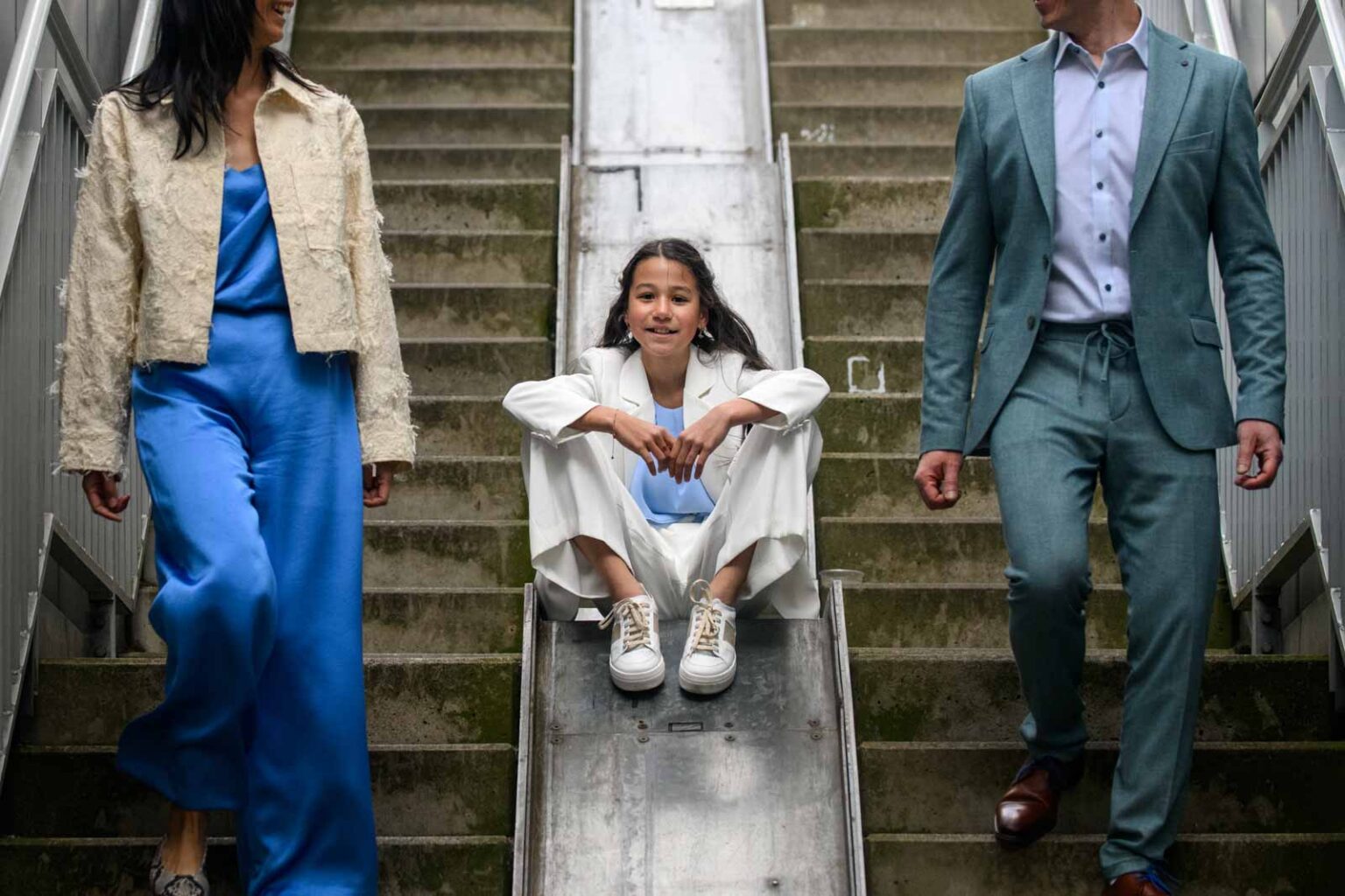 Meisje op helling, volwassenen lopen aan weerszijden trap af.